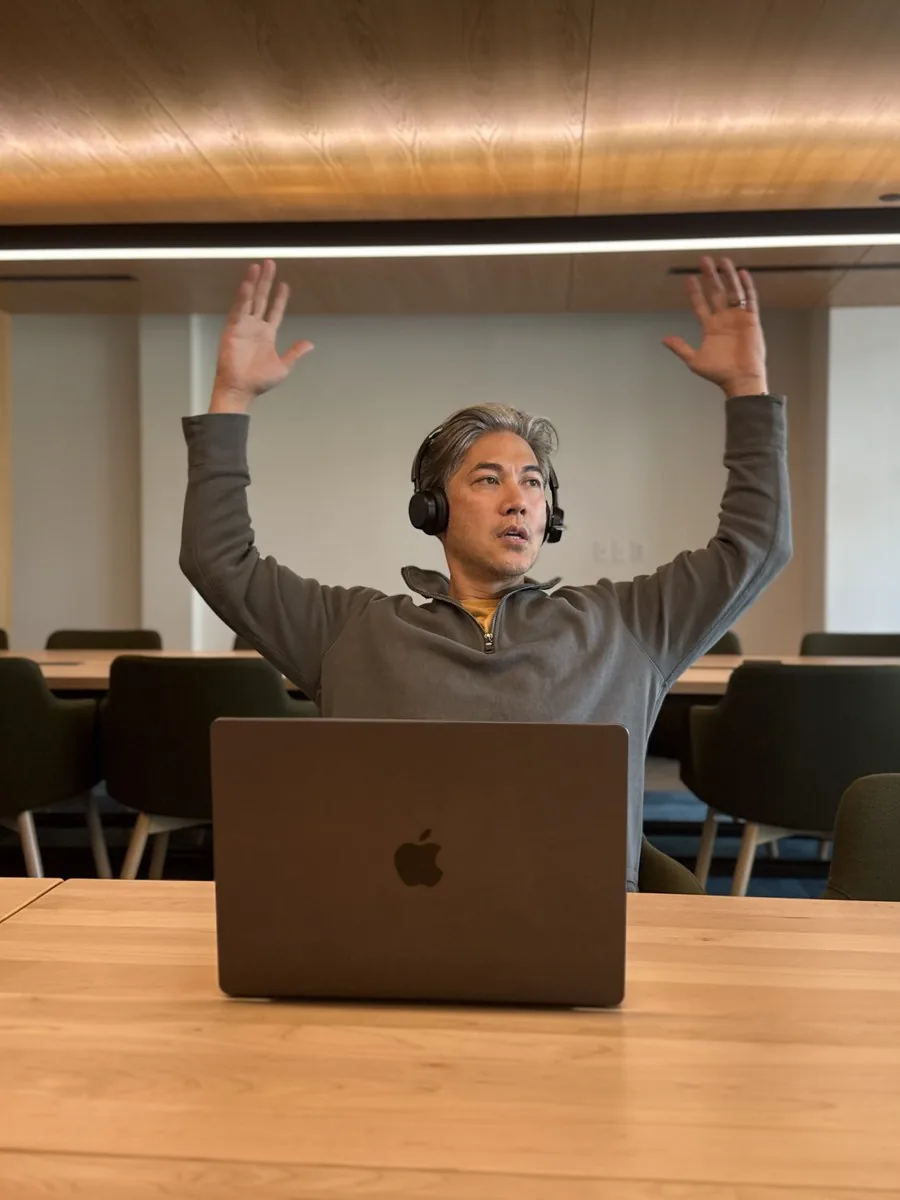 Patrick Santiago mid-session with the OpenSesame team, headset on, arms raised at a laptop